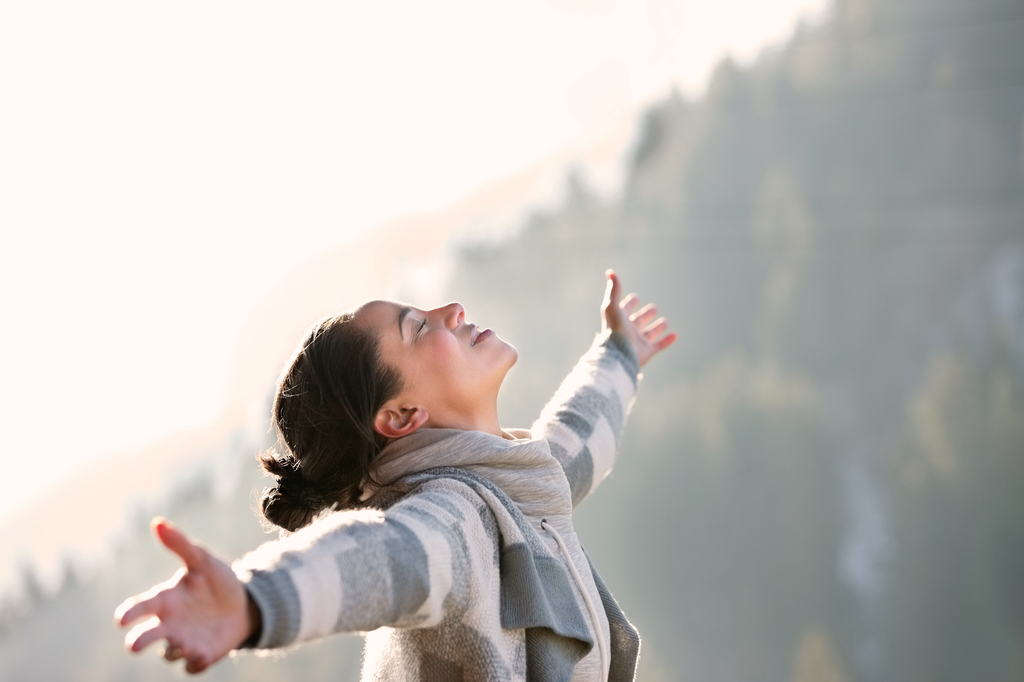 Women standing outdoors with arms outstretched feeling better after hypnotherapy session