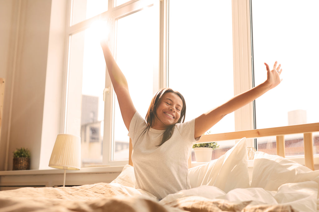 Woman in bed waking up feeling refresh and happy after a successful hypnotherapy programme